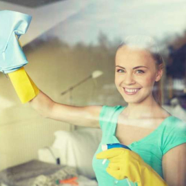 happy woman in gloves cleaning window with rag