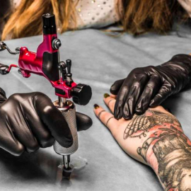 Tattooist take paint for tattoo which draws a girl